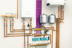 A white wall with pipes and water heaters. Providing boilers and radiant heat system services.