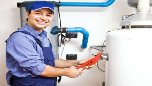 A plumber in overalls holding a wrench next to a water heater.