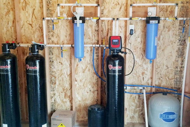 Water softener installation in a home kitchen, plumber connecting pipes and adjusting settings for efficient water treatment