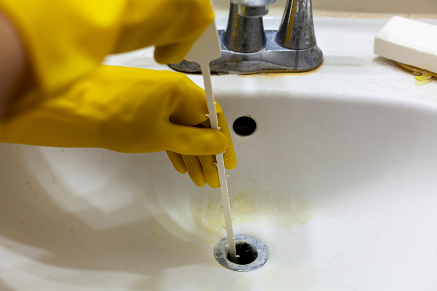 Sink being cleaned by person in yellow glove.