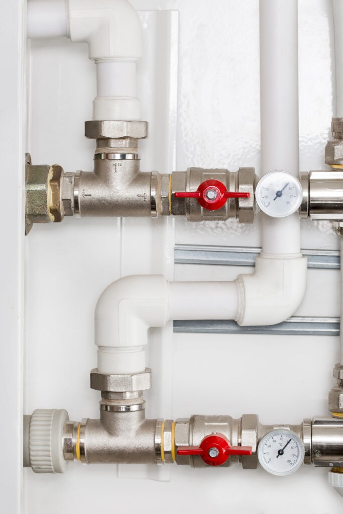 Close-up of white wall with pipes and valves.