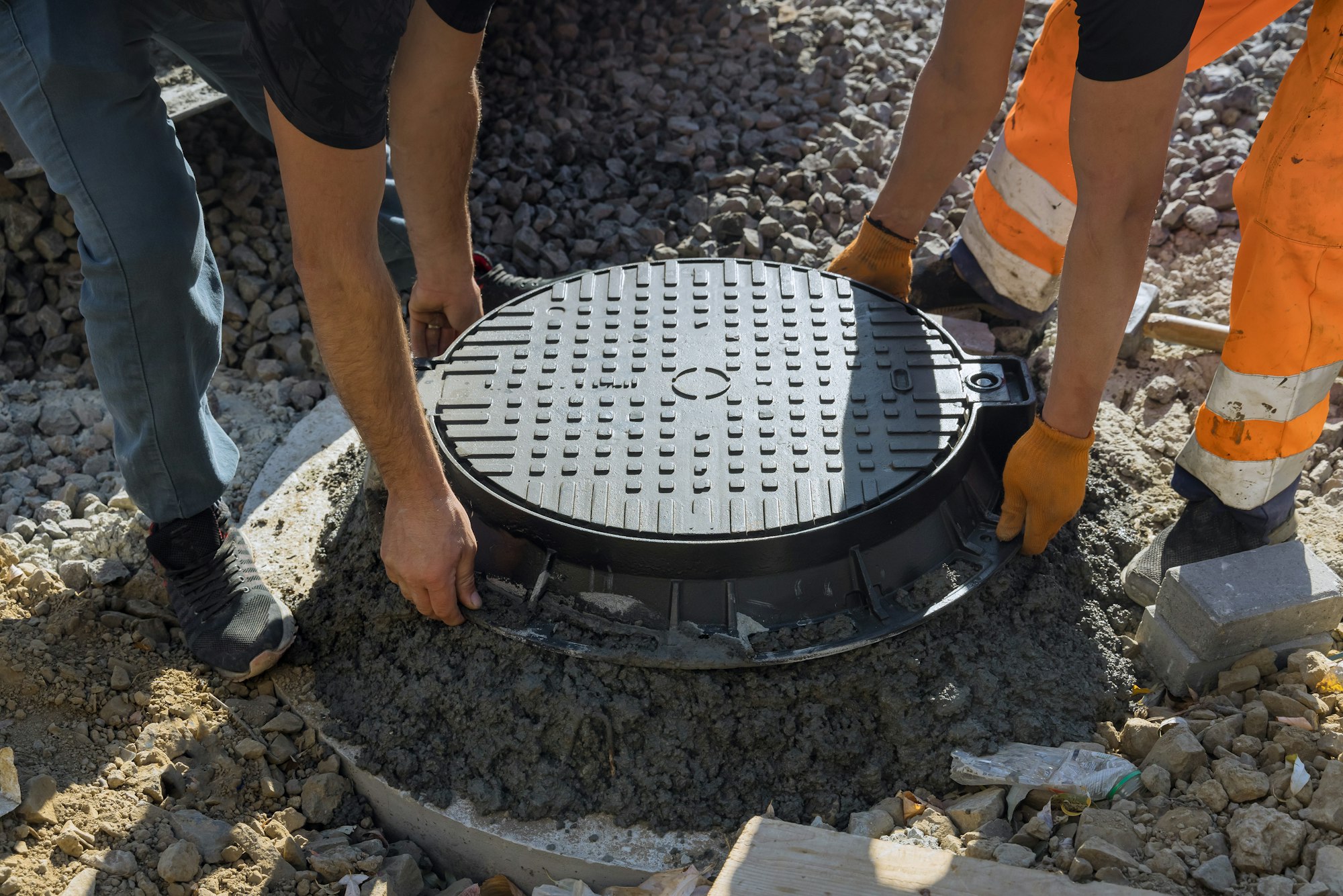 A cast iron sewer hatch is being installed in a concrete well, in preparation for the installation