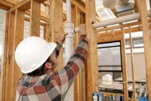 A man in a hard hat and helmet is working on constructing a wall