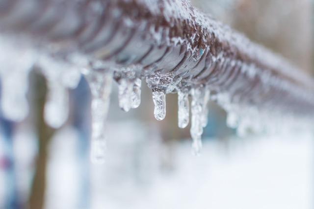 Long icicles dangling from a fence showcasing a frosty winter atmosphere